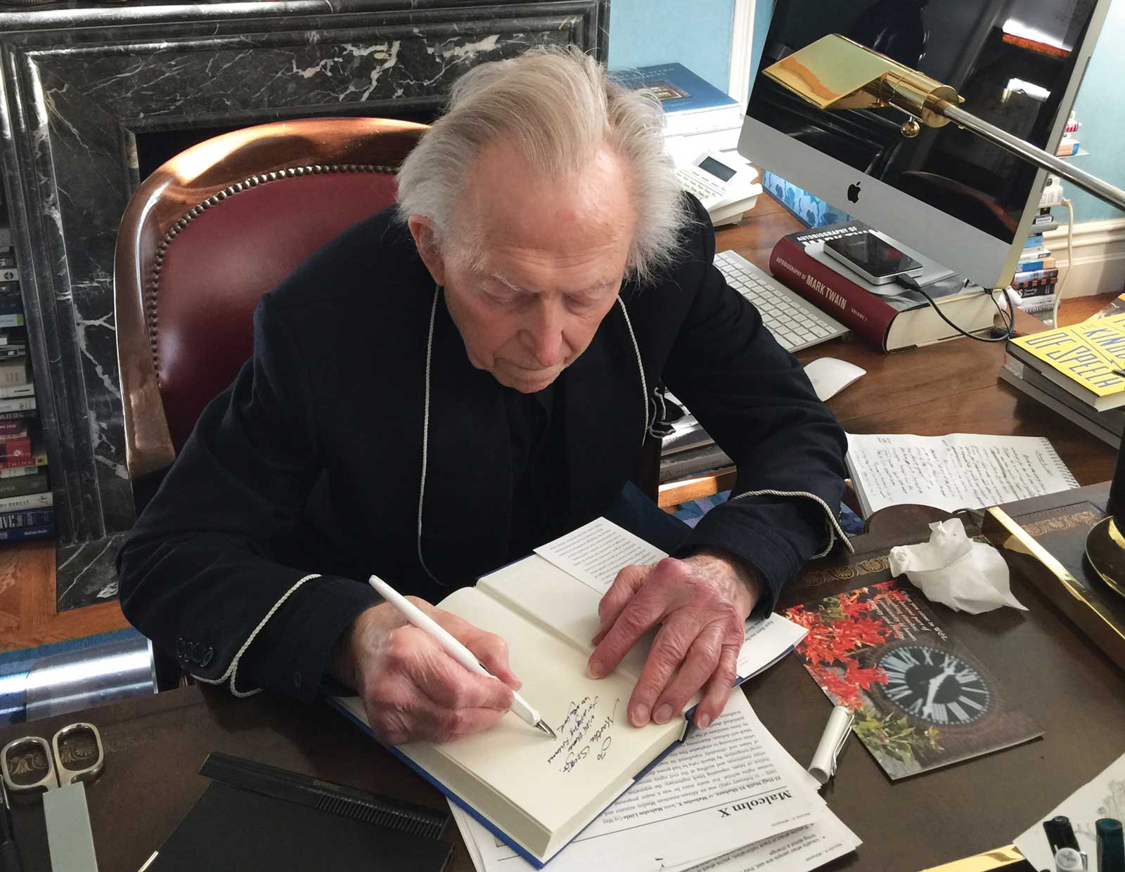 Wolfe at his desk, inscribing a book for a visitor.