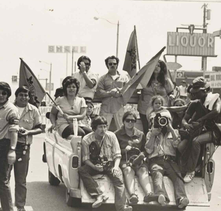 Journalists and protesters riding in the back of a pickup truck while covering a Chicano Movement protest ca. 1968-1975.